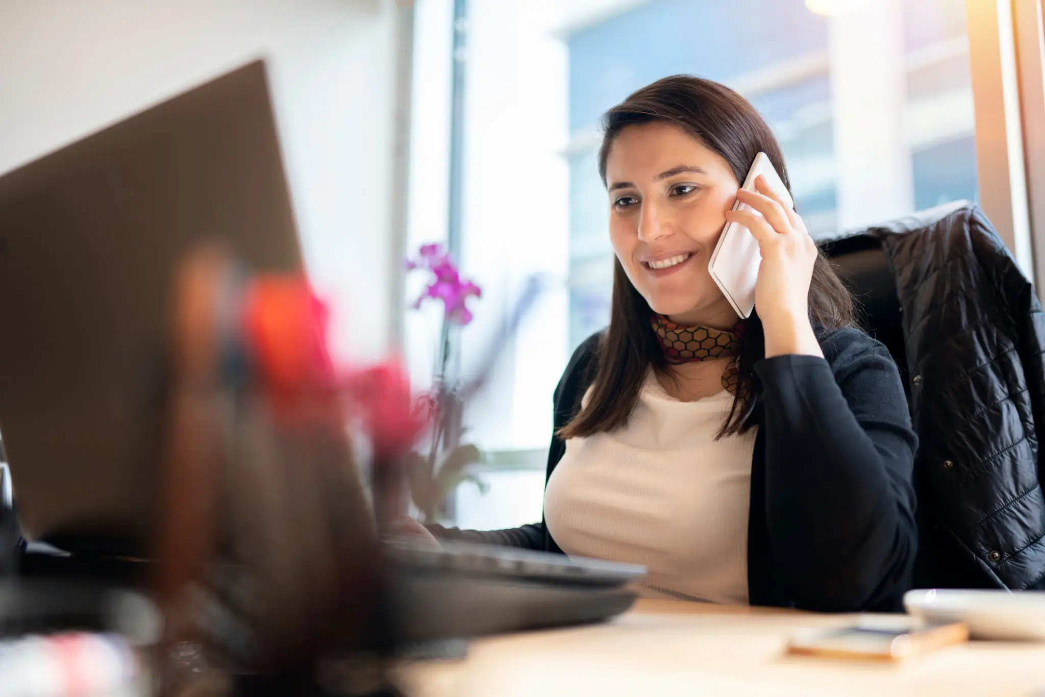 Smiling woman talking on phone at computer