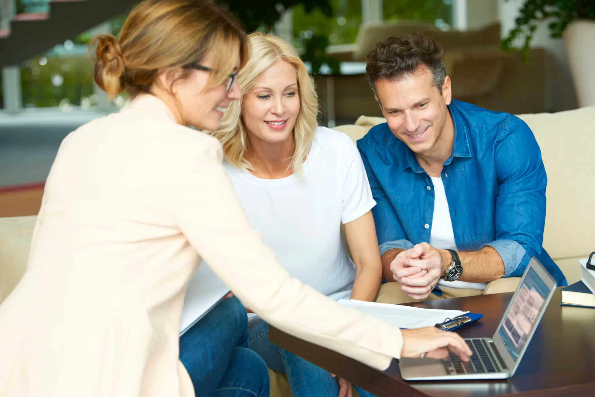 Three adults smiling while viewing laptop