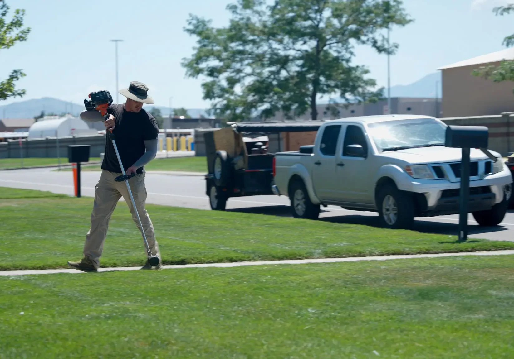 Landscaper carrying equipment on grassy lawn